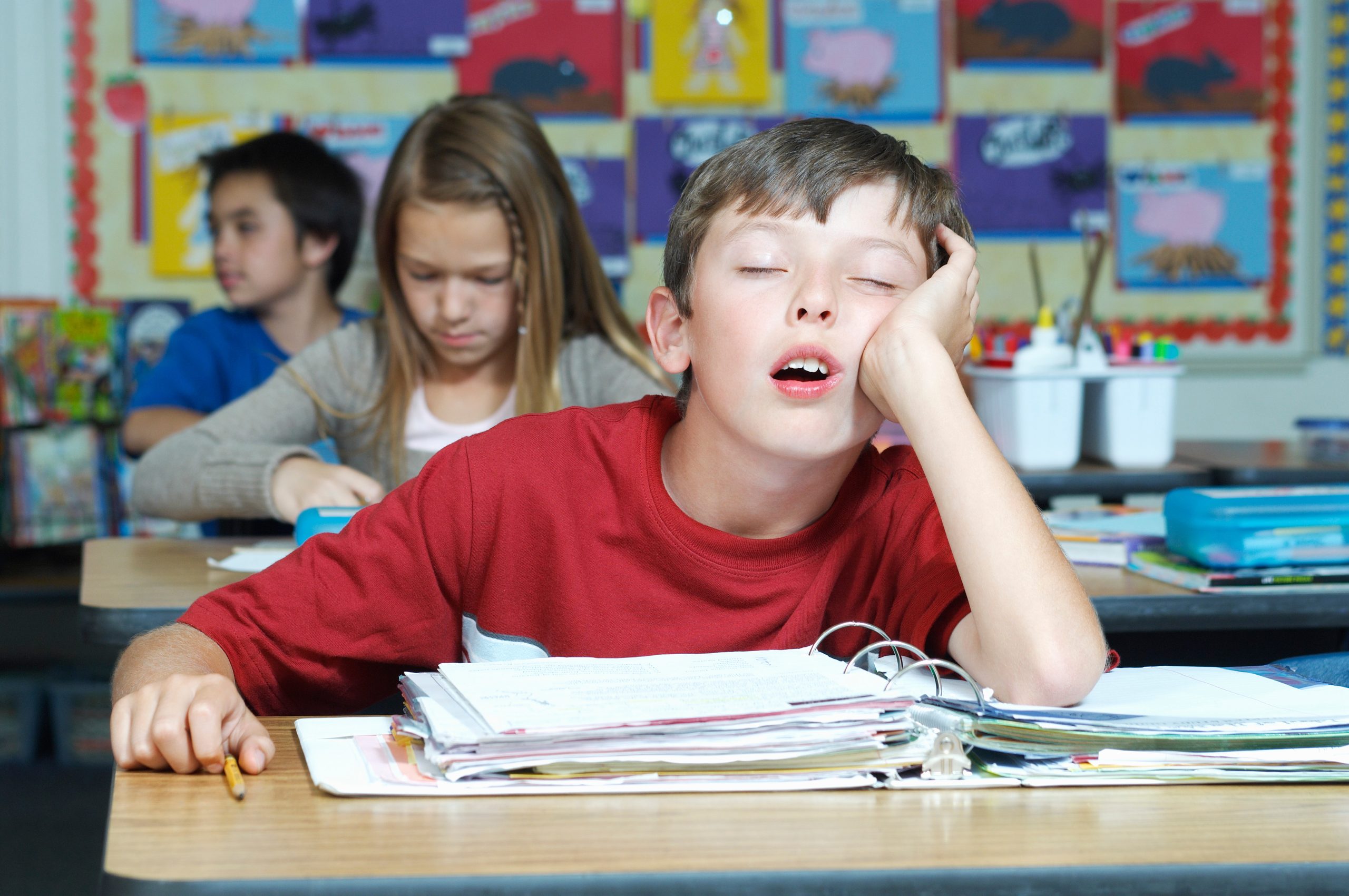 Three pupils in classroom, one of them sleeping